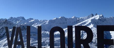 A snowy landscape with large letters spelling "VALLOIRE" in the foreground.