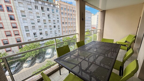Un balcon avec une table et des chaises, une vue sur le paysage urbain et un immeuble doté de nombreuses fenêtres.