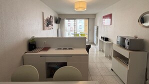 Une cuisine compacte avec un coin repas, un four à micro-ondes et un petit réfrigérateur.