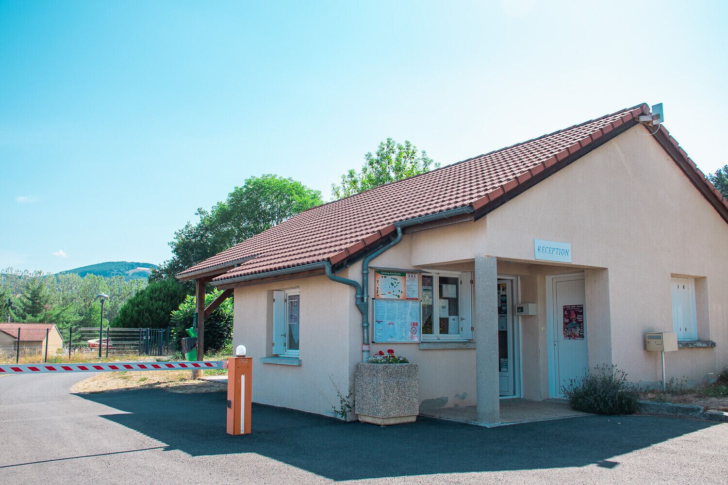 A small reception building with a tiled roof, a signboard, and a few informational posters.