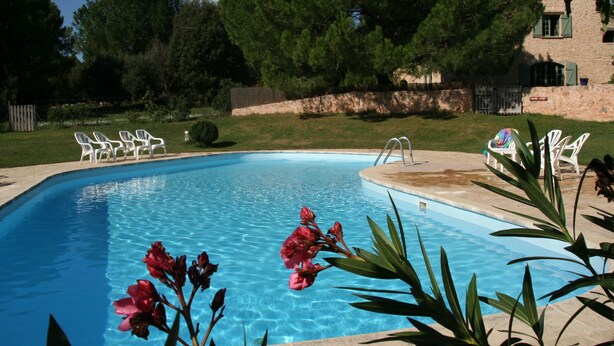 A swimming pool with clear blue water, surrounded by white lounge chairs and greenery. - Le Jas, charming Mas in Provence with shared pool, nature, calm, space (Flayosc)