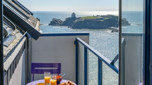 A balcony with a table set for breakfast, overlooking a coastal view with cliffs and the sea. - Seaview ! Bright veranda apartment at the foot of the beach  (Clohars-Carnoët)