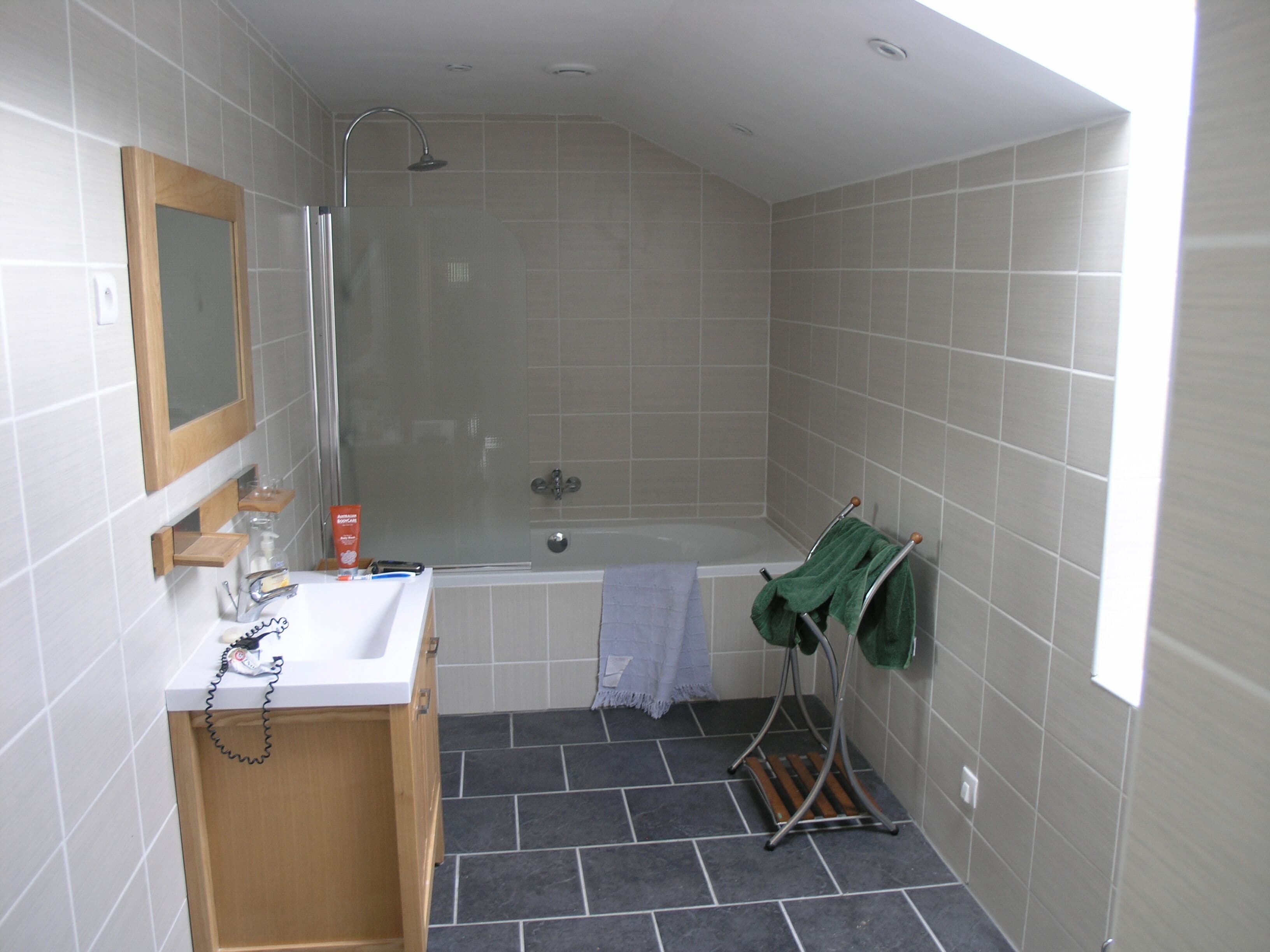 Une salle de bain avec une douche, un lavabo, un miroir et un porte-serviettes.