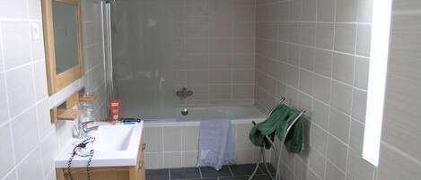Une salle de bain avec une douche, un lavabo, un miroir et un porte-serviettes.