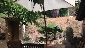 Eine Terrasse im Freien mit einem runden Holztisch und vier Holzstühlen.