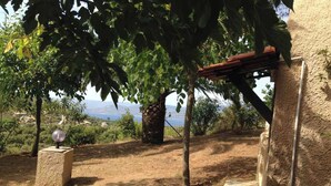 Ein rustikaler Außenbereich mit einer Pergola, Steinbänken und Blick auf die Landschaft.