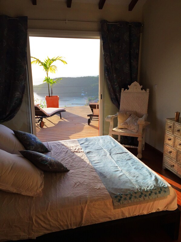 A bedroom with a bed, a chair, and a view of the sea. - Panoramic view and cozy atmosphere for this villa in Creole style (Les Anses d'Arlet)