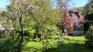 A garden with blooming trees and a stone structure. - La Flore Marine, Lovely cottage 330 m from the sea and 6 km from Étretat! (Saint-Jouin-Bruneval)