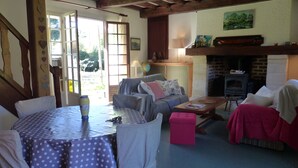 A cozy living room with a fireplace, a dining table with chairs, and a sofa. - La Flore Marine, Lovely cottage 330 m from the sea and 6 km from Étretat! (Saint-Jouin-Bruneval)