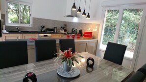 Une cuisine moderne avec un coin repas, comprenant une table en marbre, des chaises noires et une plante en pot.