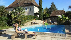 Area della piscina con una poltrona da relax, una piscina e una casa sullo sfondo.