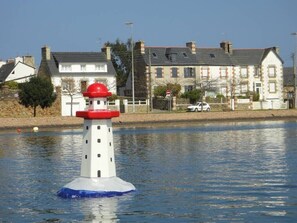 Un phare se dresse sur une étendue d’eau, avec des immeubles résidentiels en arrière-plan.