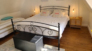 Ein ordentlich eingerichtetes Schlafzimmer mit einem Bett, Nachttischen und einem kleinen Holzschrank.