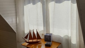 Ein Zimmer mit einem Holztisch, einem Modellsegelboot und einer kleinen Lampe.