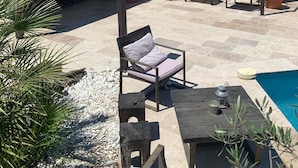 En patio med udendørs møbler, en pool og et overdækket område med grill.