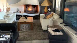 En moderne stue med pejs, sofa, sofabord og fjernsyn.