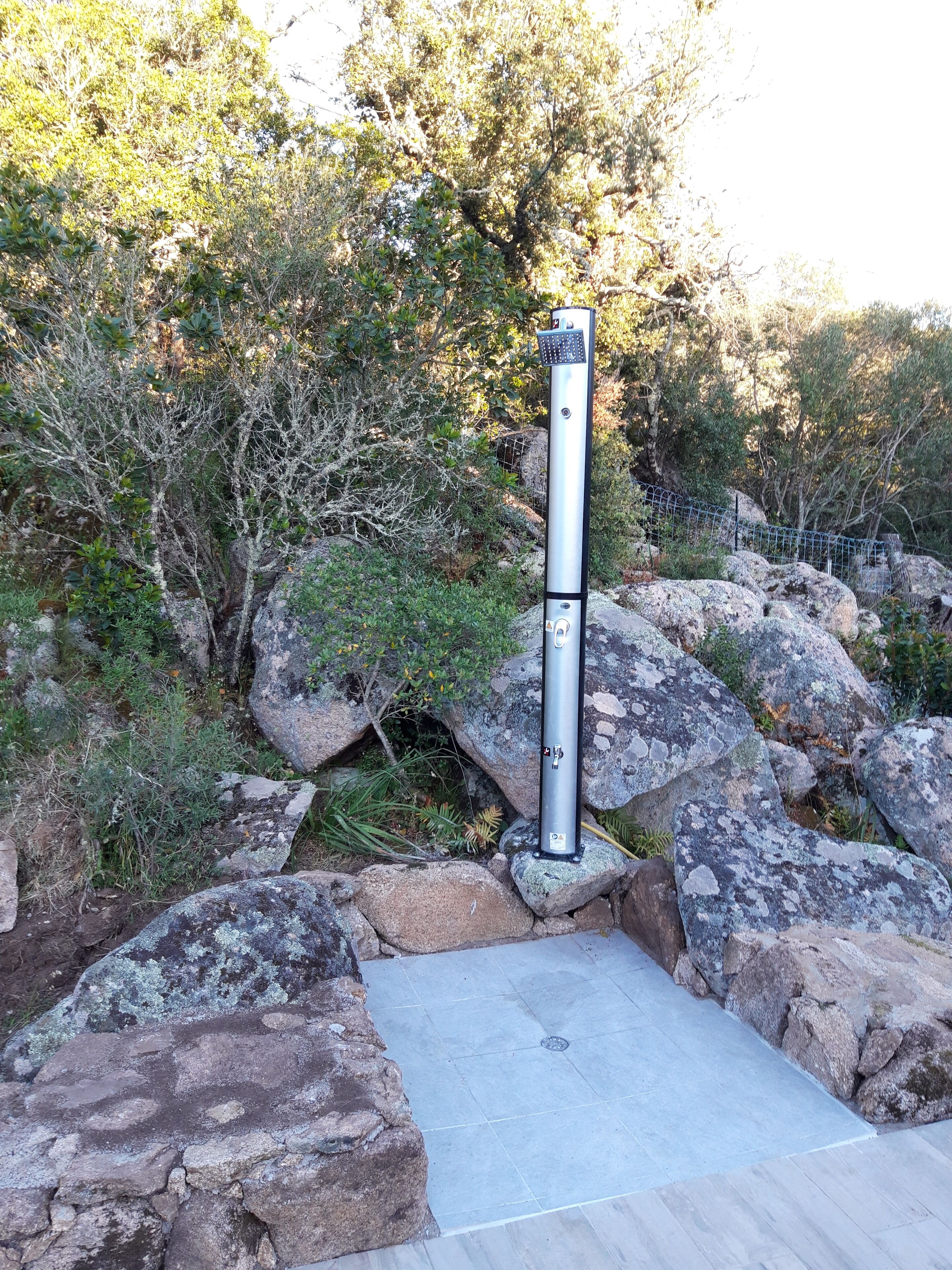 A metal structure with a keypad, surrounded by rocks and vegetation.