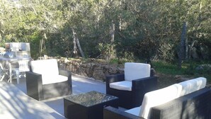 An outdoor seating area with wicker furniture and a stone wall backdrop. - CHARMING VILLA WITH PRIVATE POOL 4 TO 5 PEOPLE NEAR PALOMBAGGIA (PORTO VECCHIO)