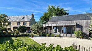 A modern house with a stone facade, a covered patio, and a well-maintained garden. - Great longère ideally located (Arradon)