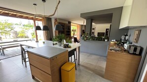 A modern kitchen with a central island, wooden cabinets, and a yellow trash bin. - Great longère ideally located (Arradon)