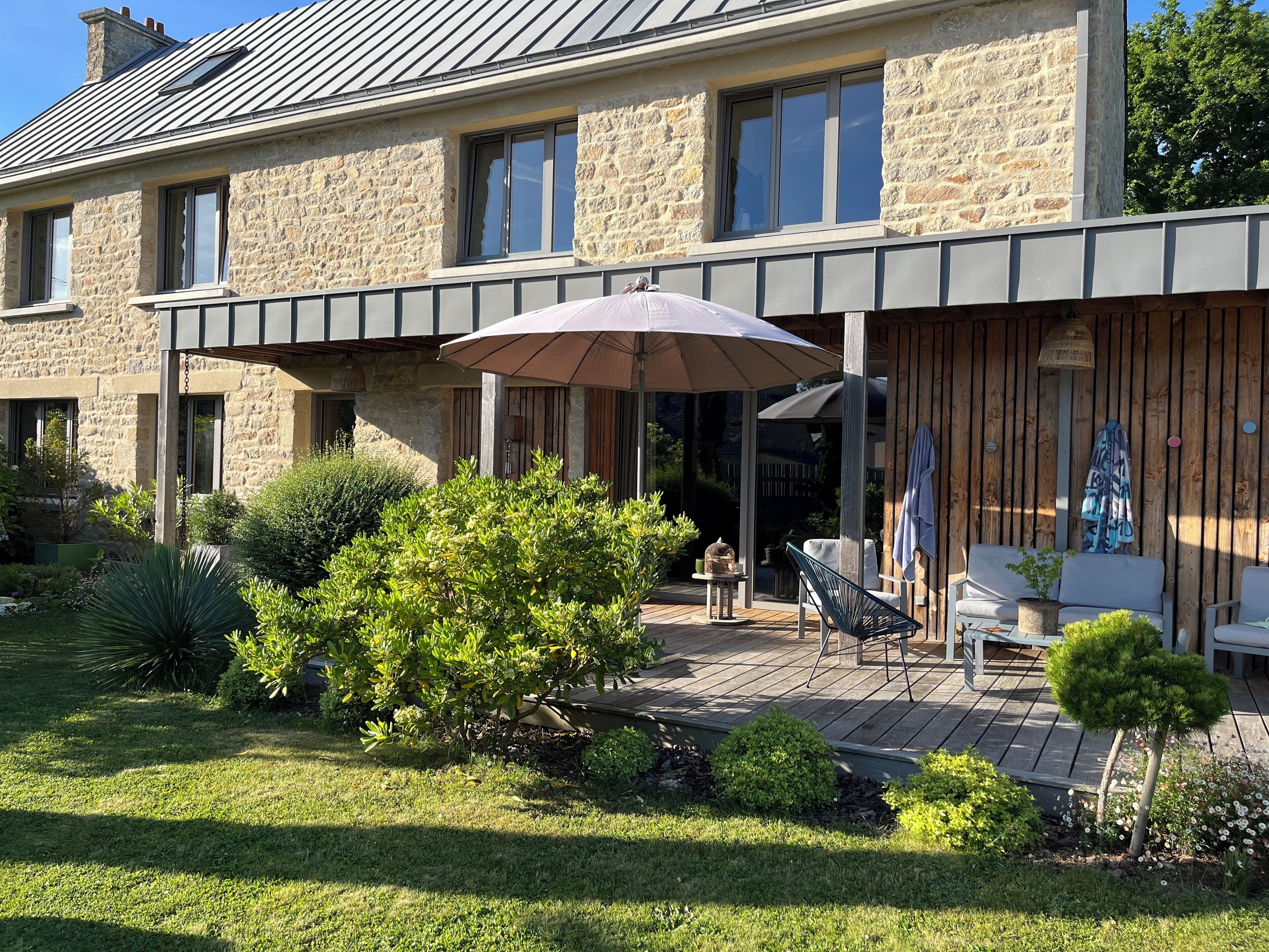 Ein Steinhaus mit überdachter Terrasse, Gartenmöbeln und einem Garten.