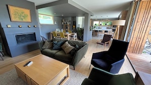 A modern living room with a fireplace, a dining area, and a kitchen in the background. - Great longère ideally located (Arradon)