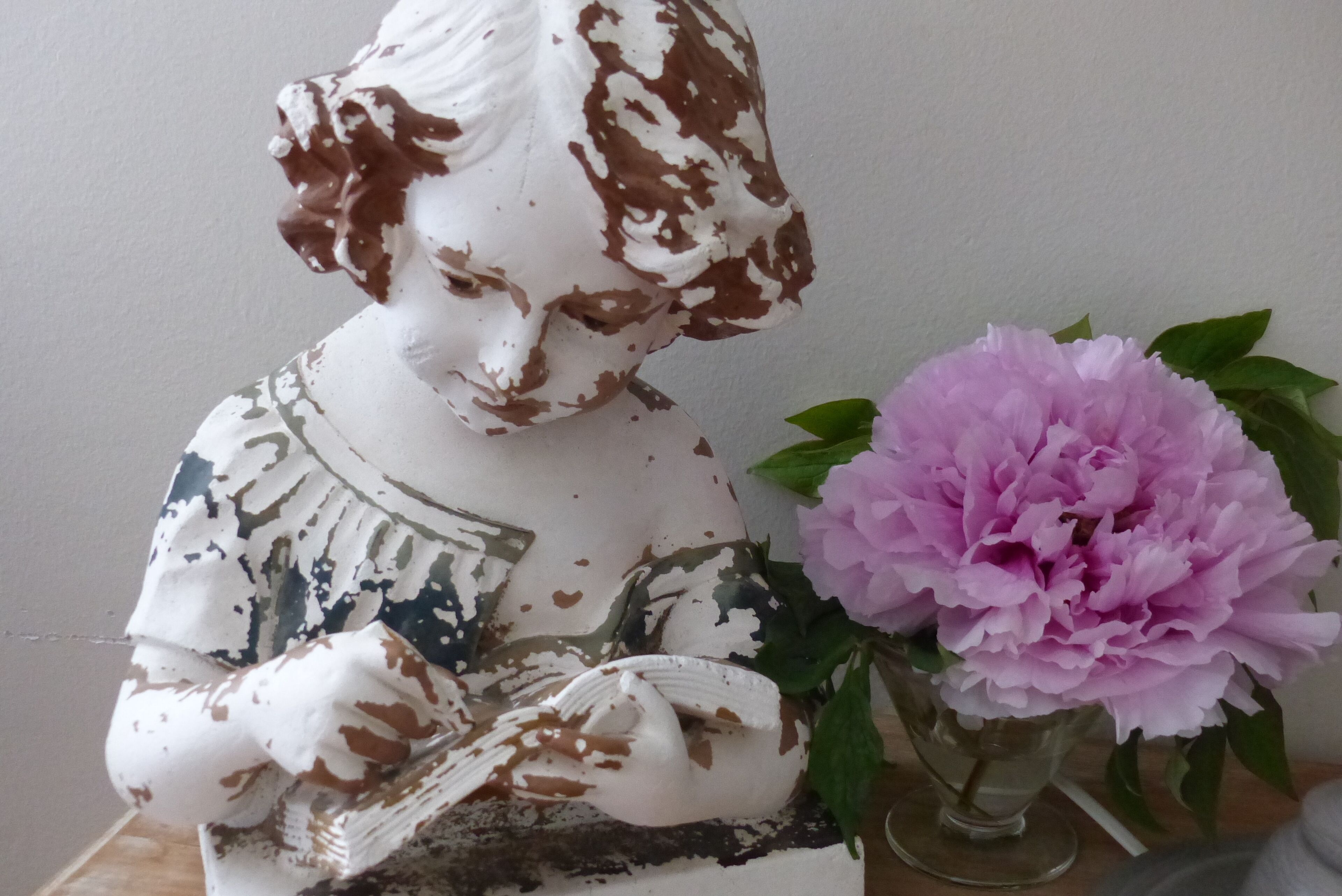 A statue with a floral pattern on its surface, placed next to a vase with a pink flower.