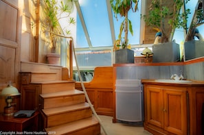 Step up to a balcony with a view, featuring a vanity, table, and potted plants.