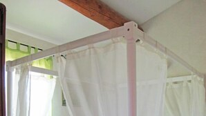 Ein Bett mit Baldachin in einem Zimmer mit Holzboden und grüner Wand.