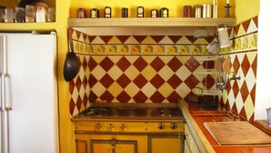 Une cuisine avec un poêle jaune, un réfrigérateur blanc et un crédence à motifs rouges et blancs.