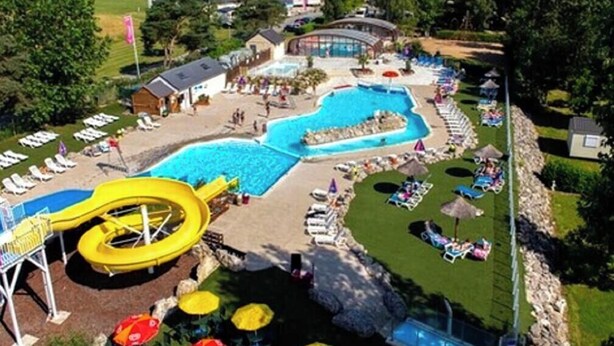 Um resort com uma grande piscina, um toboágua e espreguiçadeiras.
