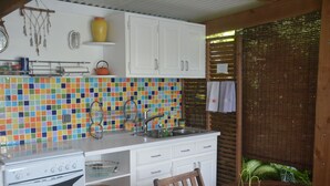 Een compacte keuken met een betegelde spatwand, witte keukenkastjes, een fornuis en een eettafel met stoelen.