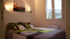 Un dormitorio con una cama, un cuadro en la pared y una ventana con vistas al exterior.