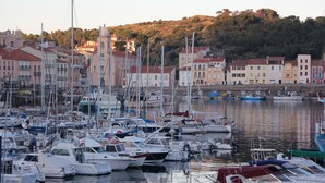 Un puerto deportivo con numerosas embarcaciones amarradas, rodeado de edificios con techos rojos y una colina al fondo.