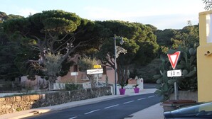 Vista de la calle con una señal que indica una distancia de 50 metros, un edificio con el rótulo 'Portimondes' y un muro de piedra.
