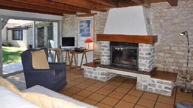 A cozy living area with a stone fireplace, a comfortable sofa, and a television.