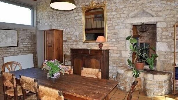 Un comedor rústico con pared de piedra, mesa de madera y sillas.