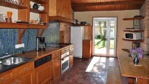 Una cocina con armarios de madera, salpicadero de azulejos, horno empotrado y refrigerador.
