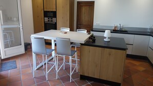 A modern kitchen with a white table, grey chairs, wooden cabinets, and a black countertop.