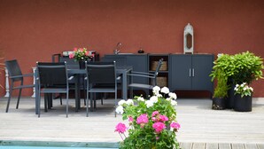 An outdoor patio area with a pool, a dining table with chairs, and potted plants.