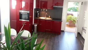 A compact kitchen with red cabinets, a stainless steel oven, a sink, and a coffee maker.