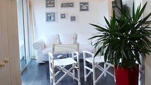 A modern interior with a dining area, white furniture, and a large potted plant.