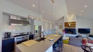 A modern kitchen with a central island, stainless steel appliances, and a dining area with a sofa and TV. - LAKEFRONT (private quay)-SPA-BILLARD-PING PONG-WORKING TABLE (Mille-Isles)