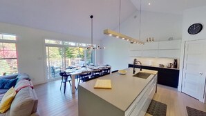 A modern kitchen with a central island, dining area with chairs, and a large window providing a view of the outdoors. - LAKEFRONT (private quay)-SPA-BILLARD-PING PONG-WORKING TABLE (Mille-Isles)