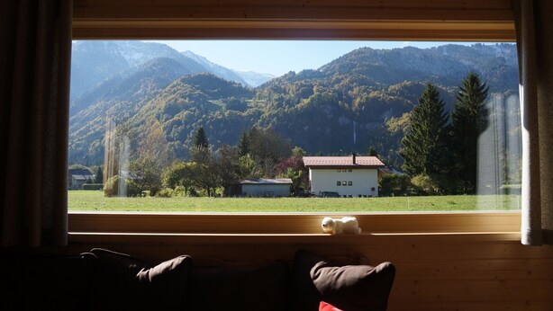 A room with a large window overlooking a mountainous landscape, a small white teddy bear on the windowsill, and a wooden ceiling. - 50m from the ski bus, slopes 5min, 4 * Family Chalet with parking and Wifi (Samoëns)