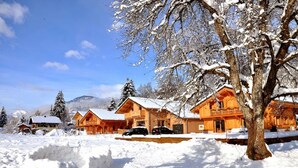 A wooden lodge with multiple cabins, surrounded by snow-covered trees and mountains in the background. - 50m from the ski bus, slopes 5min, 4 * Family Chalet with parking and Wifi (Samoëns)