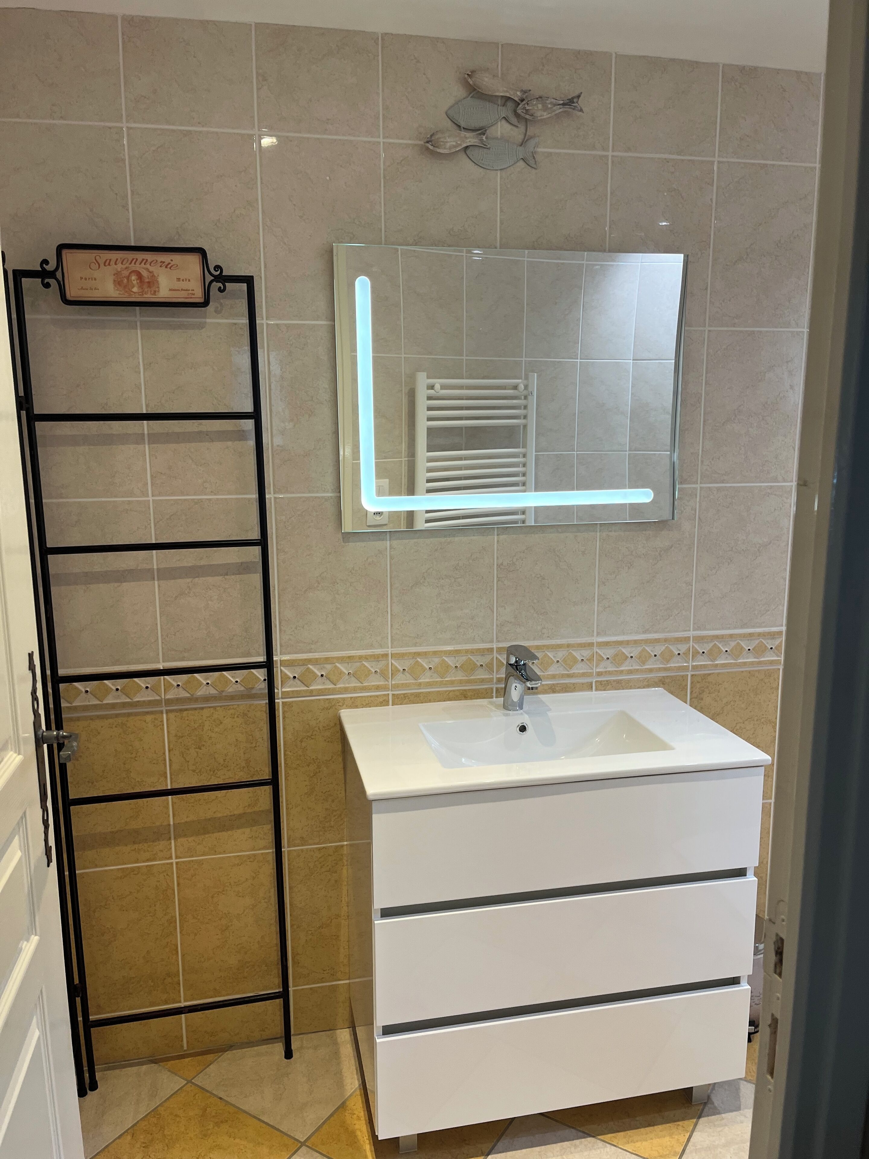 A bathroom with a white sink, a mirror, and a towel rack.