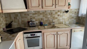 Cocina con armarios de madera, un tostador, un fregadero y un lavavajillas.