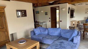 Una sala de estar con un sofá azul, una mesa de centro de madera y un comedor con mesa y sillas.