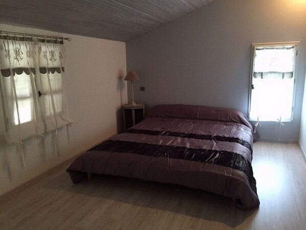A bedroom with a bed, a nightstand, a lamp, and a window with curtains.